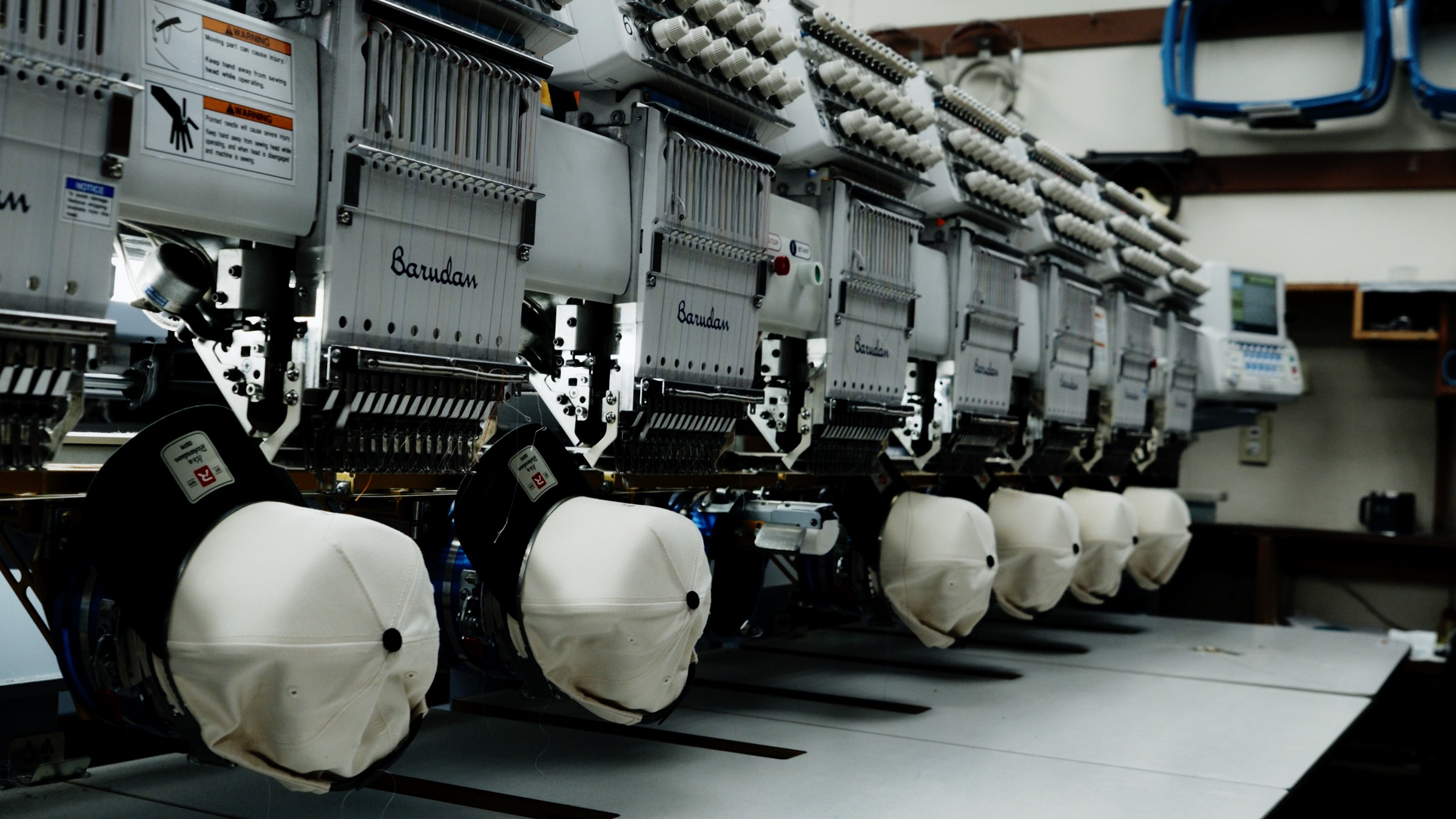 Barudan embroidery machines stitching white caps