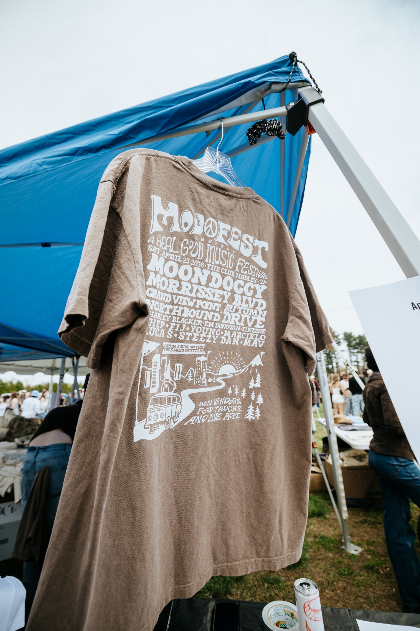 Brown MOJOFEST lineup shirt displayed at the merchandise tent