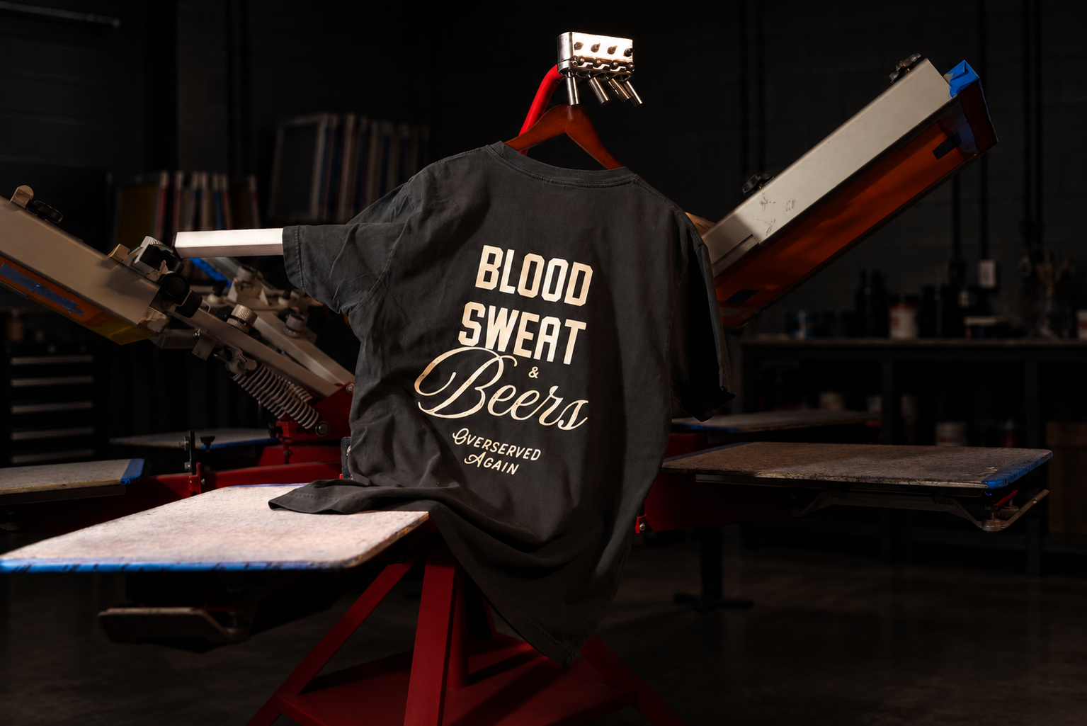 Overserved Again printed T-shirt on a screen-printing press